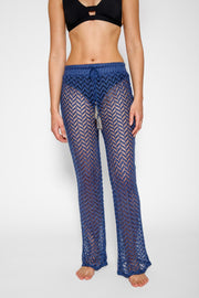 Brunette model facing front close up, wearing Navy Zuma Pants with sheer chevron lace fabric, elasticated drawstring waist with gold accents, and a slight flare at the hem. Koy Resort affordable vacation, cruise, and resort-wear.