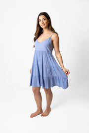 Brunette model facing front, wearing Bahama Blue Miami Tiered Strappy Mini Dress. Features adjustable straps, a flirty tiered empire silhouette, smocked back, and pockets. Crafted from lightweight rayon and lined in white. Perfect for date night or any vacation-ready occasion. Koy Resort affordable vacation, cruise, and resort-wear.