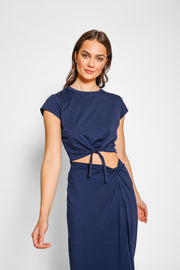 Brunette model close up, wearing Navy Laguna Beach Side Knot Skirt with matching top, featuring a stylish tie knot accent at the waist and a thigh-high slit. Koy Resort affordable vacation, cruise, and resort-wear.