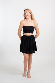 Blonde model facing front, wearing Black Miami Smocked Bandeau Top with a smocked elastic chest, cropped style, and bandeau design. Perfect for mixing and matching outfits. Koy Resort affordable vacation, cruise, and resort-wear.