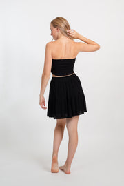 Blonde model facing back, wearing Black Miami Smocked Bandeau Top with a smocked elastic chest, cropped style, and bandeau design. Perfect for mixing and matching outfits. Koy Resort affordable vacation, cruise, and resort-wear.