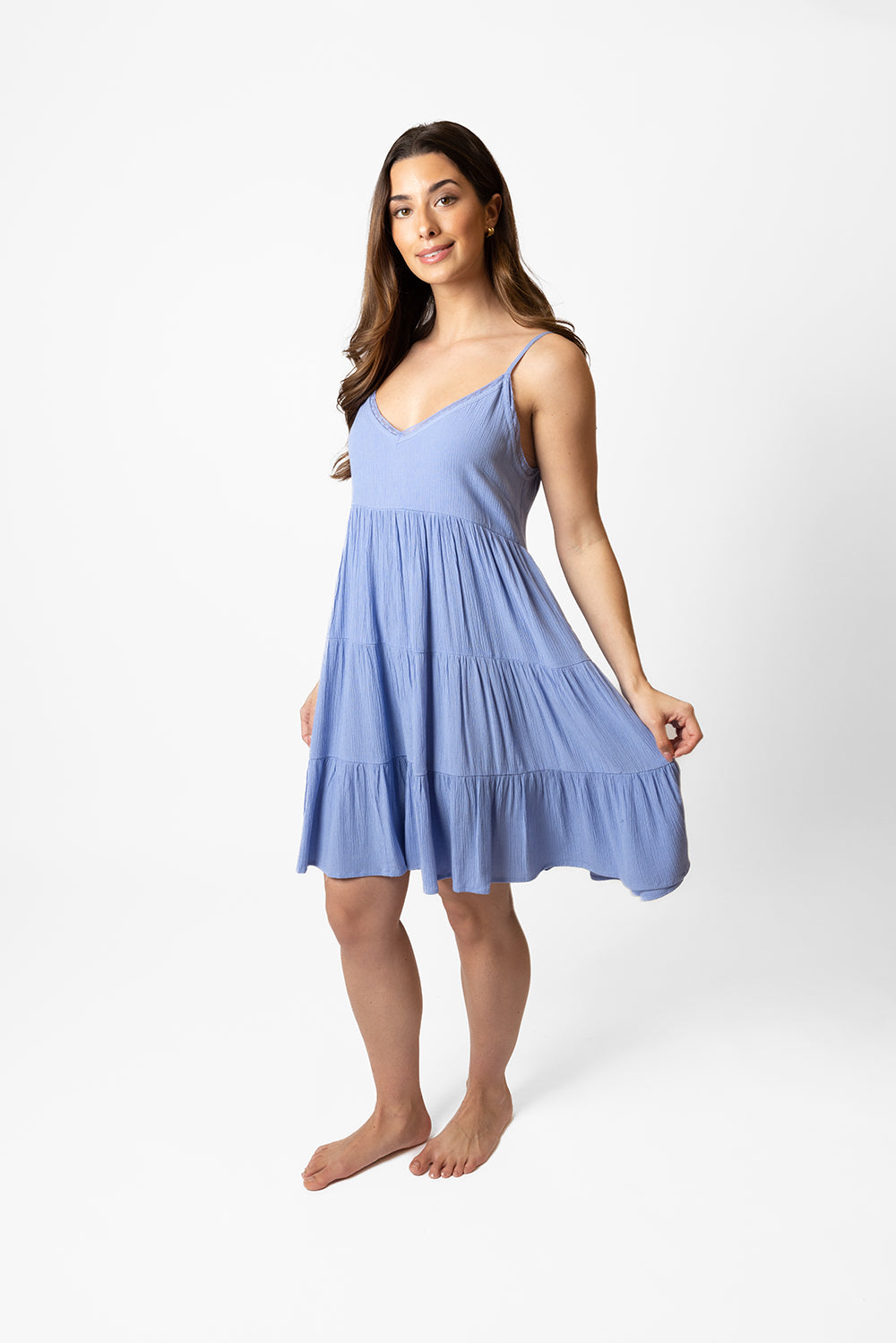 Brunette model facing front, wearing Bahama Blue Miami Tiered Strappy Mini Dress. Features adjustable straps, a flirty tiered empire silhouette, smocked back, and pockets. Crafted from lightweight rayon and lined in white. Perfect for date night or any vacation-ready occasion. Koy Resort affordable vacation, cruise, and resort-wear.