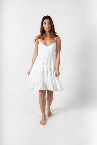 a front shot of a brunette hair woman wearing a white spaghetti strap mini summer dress