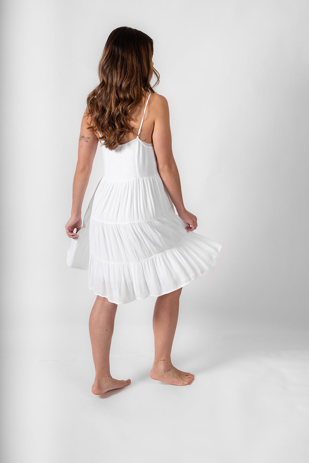 the back of a bruntte hair woman model wearing a white strappy beach dress