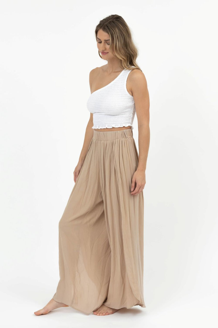 Woman wearing a white top and beige wide-leg pants on a white background