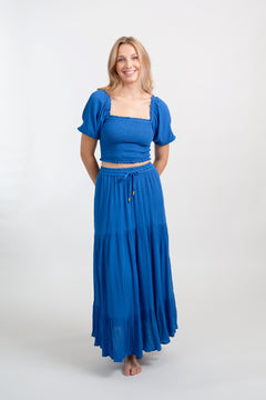 Blonde model facing front, wearing Blue Cobalt Miami Boho Smocked Crop Top. Features a lightweight crinkle rayon fabric, flattering smocked detailing, flowy sleeves, and a cropped fit. Ideal for adding a boho chic touch to your summer wardrobe, perfect for travel and various occasions. Koy Resort affordable vacation, cruise, and resort-wear.