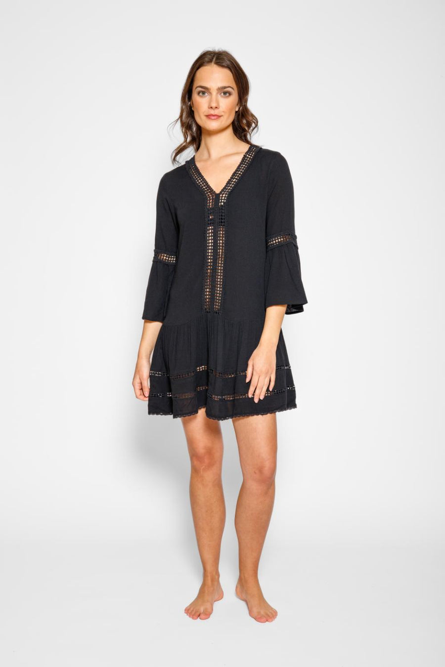 Brunette model facing front, wearing Black Miami Luxe Drop Waist Dress with luxury lace trim, drop waist, v-neck, and flutter sleeves. Fun and flirty short dress perfect for any occasion. Koy Resort affordable vacation, cruise, and resort-wear.