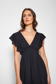 Brunette model facing front close up, wearing Black Miami Luxe Ruffle Sleeve Maxi Dress with ruffle sleeves, deep v-neck, semi-exposed back, empire waist, luxury crochet details, and frill hem. Koy Resort affordable vacation, cruise, and resort-wear.