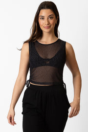 Brunette model facing front close up, wearing Black Seascape Mesh Gathered Tank Top with a dark tonal floral print, adjustable side gathering, sheer fabric, and high scoop neck. Koy Resort affordable vacation, cruise, and resort-wear.