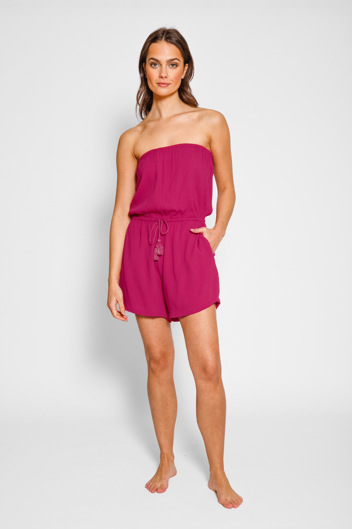 Woman wearing a strapless pink romper on a white background