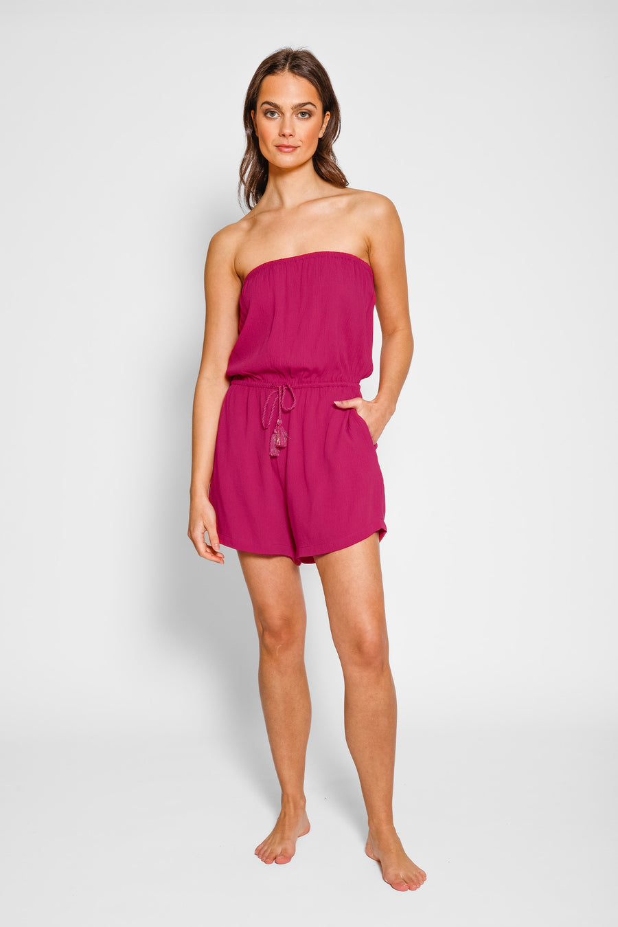 Woman wearing a strapless pink romper on a white background
