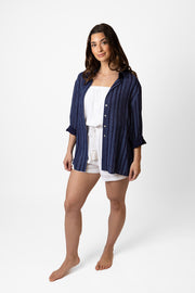 Brunette model facing front, wearing a navy Marina Stripe Relaxed Button Up Shirt. Features a relaxed fit, collar, white tone buttons, roll-up sleeves, and a tonal mock stitch print. Perfect for any occasion, combining style and comfort. Koy Resort affordable vacation, cruise, and resort-wear.