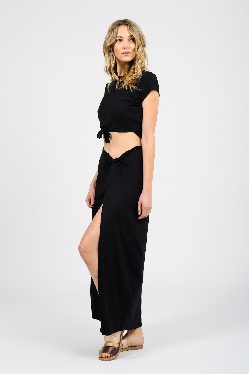 Blonde model wearing black laguna side knot maxi slit skirt facing side. Paired with Laguna knot top in black from Koy Resort. Koy Resort vacation cruise wear.