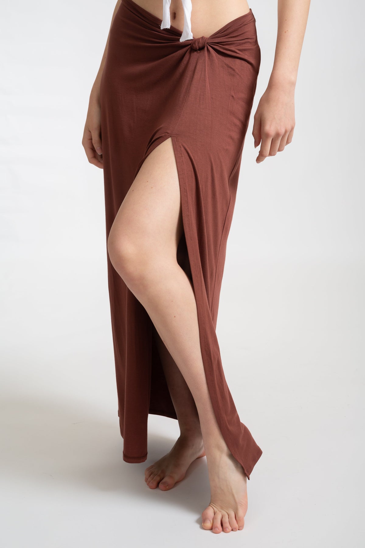 Model wearing mocha brown laguna side knot maxi skirt facing front up close. Koy Resort vacation cruise wear.