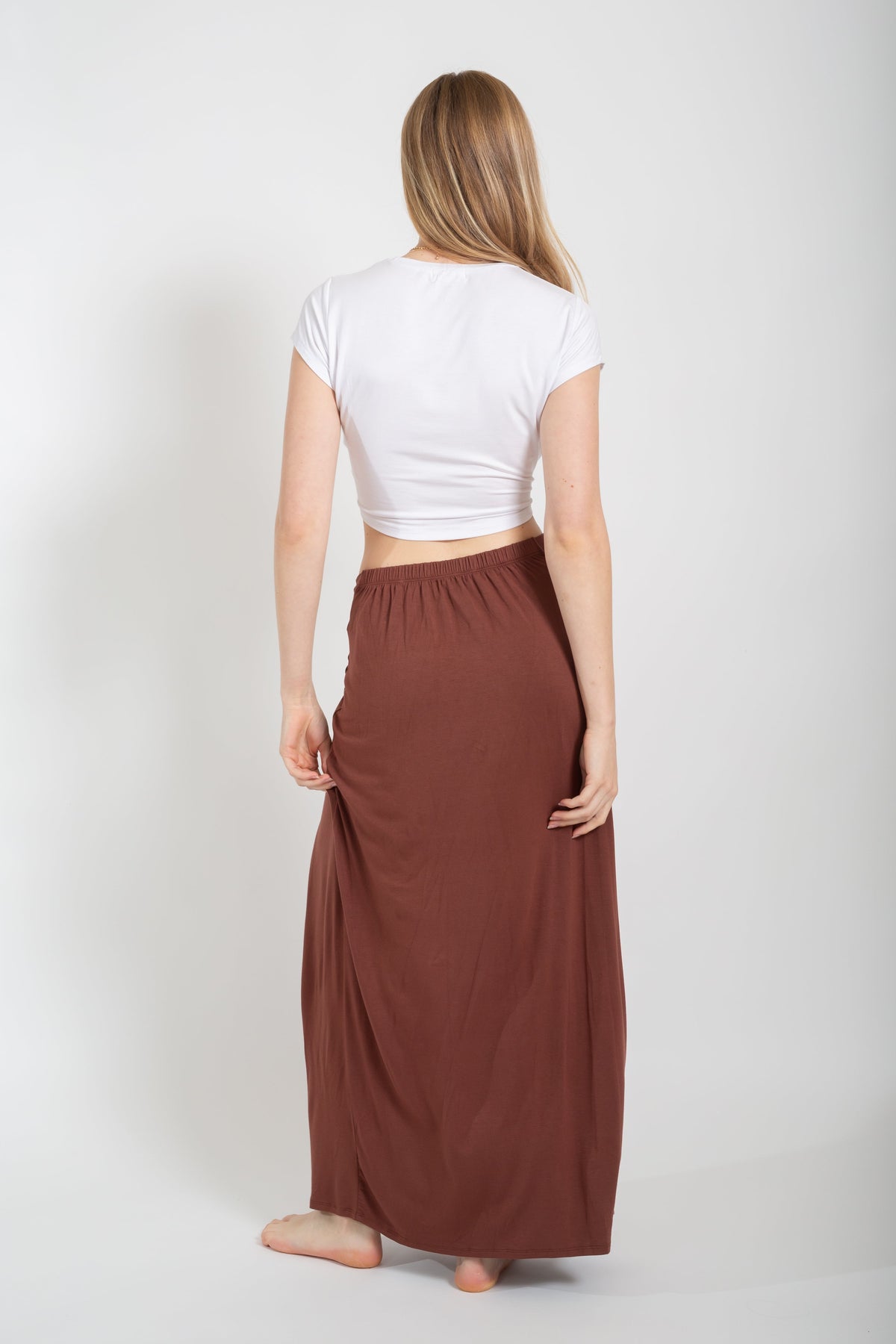 Blonde model wearing mocha brown laguna side knot maxi slit skirt facing back. Paired with Laguna knot top in white from Koy Resort. Koy Resort vacation cruise wear.