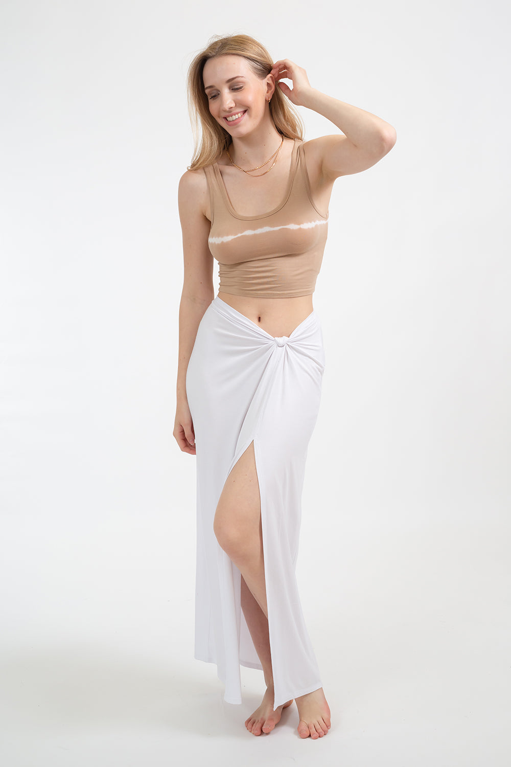 Blonde model wearing white laguna side knot maxi skirt facing front. Paired with Buzios crop tank in sand colour from Koy Resort. Koy Resort vacation cruise wear.