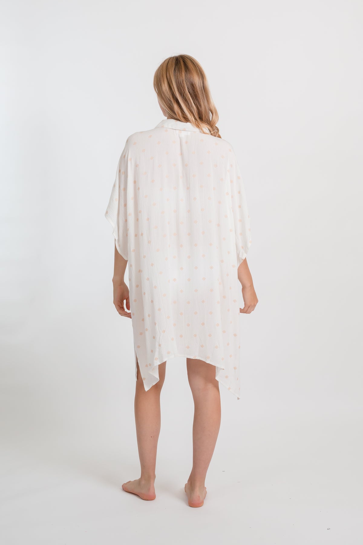 the back of a blonde hair female model wearing a white with gold dot print big shirt dress
