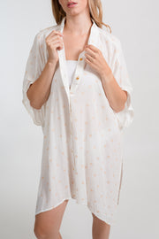 a zoomed in photo of a female model wearing a white with dot print big shirt dress buttoned down as a bikini cover up