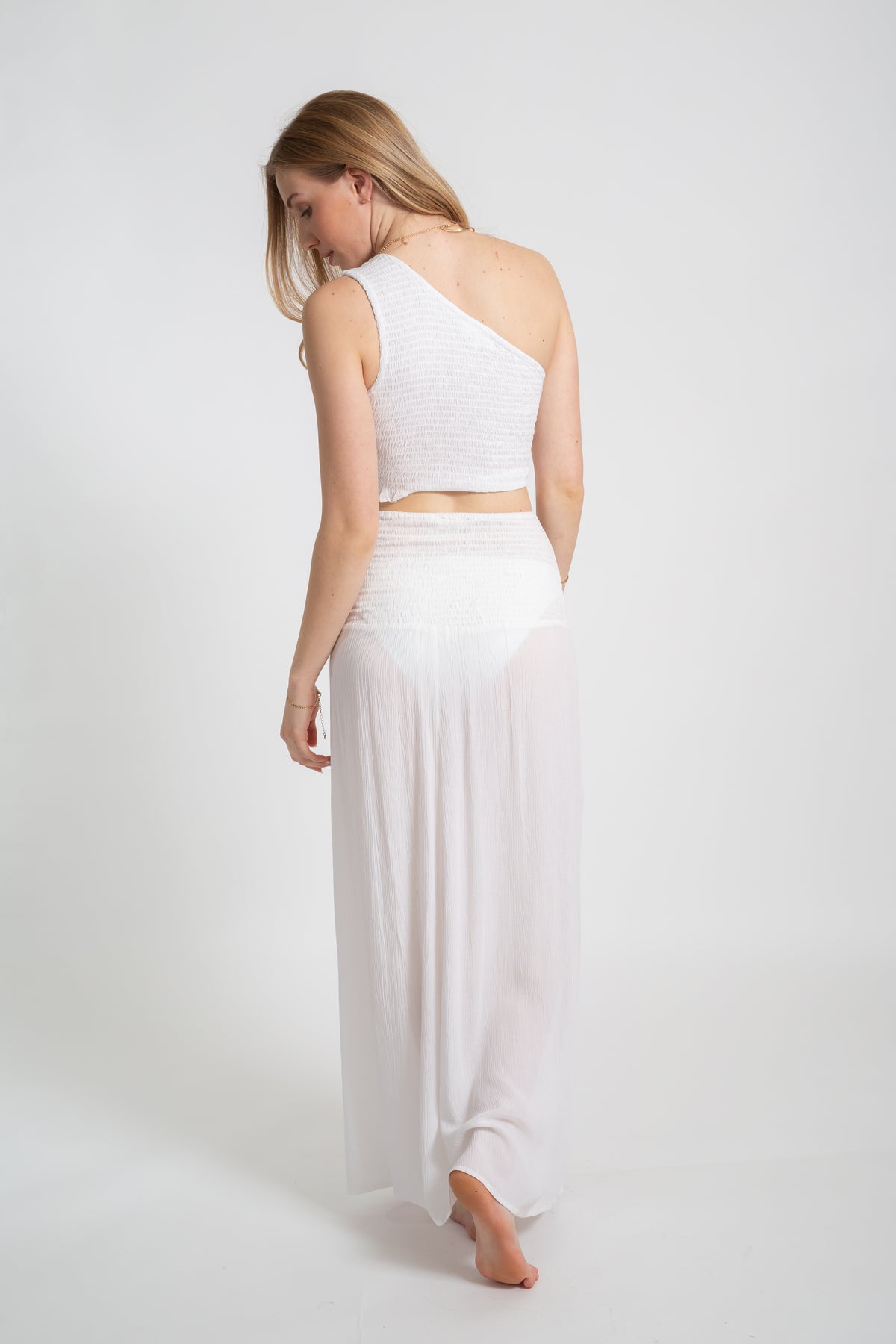 Blonde model wearing the white Miami convertible skirt with sexy slit facing back. Paired with the Miami smoked crop top in white by Koy Resort Summer collection.
