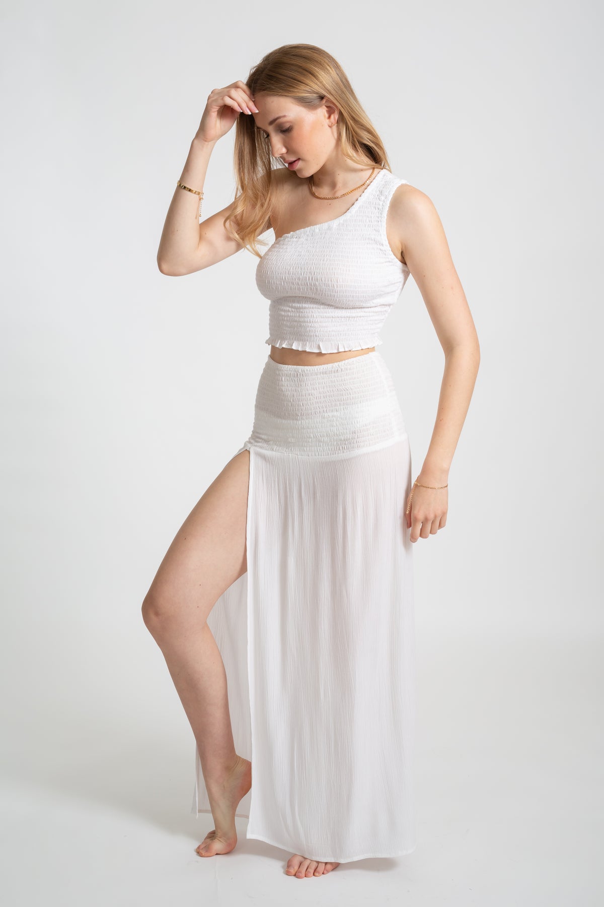 Blonde model wearing the white Miami convertible skirt with sexy slit facing side. Paired with the Miami smoked crop top in white by Koy Resort Summer collection. 