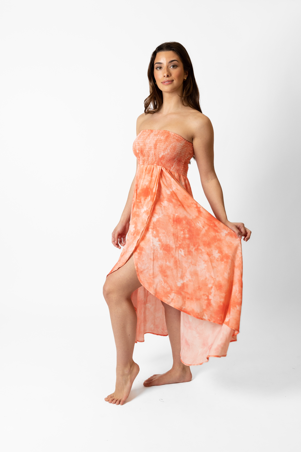 A woman wearing coral tie-dye inspired beach cover up dress. Woman's outfit and pose suggesting a confident and stylish attitude.