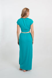 the back of a blonde hair woman model wearing matching aqua color top and skirt from Koy Resort