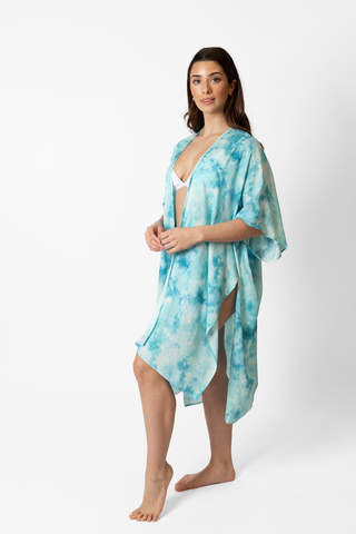 woman standing wearing a blue tie-dye kimono style beach cover up being confident