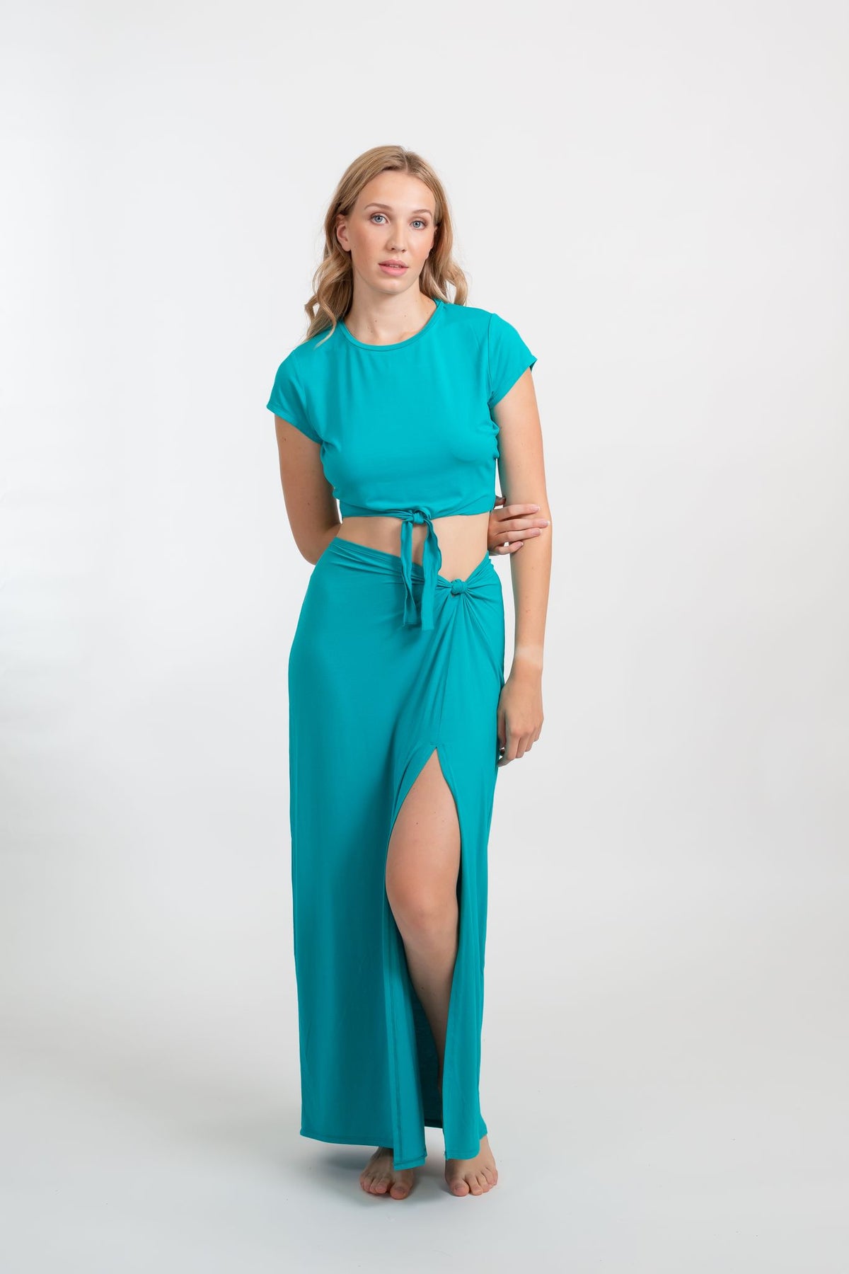 a front shot of a female model wearing matching auqamarin color crop top and maxi side slit skirt